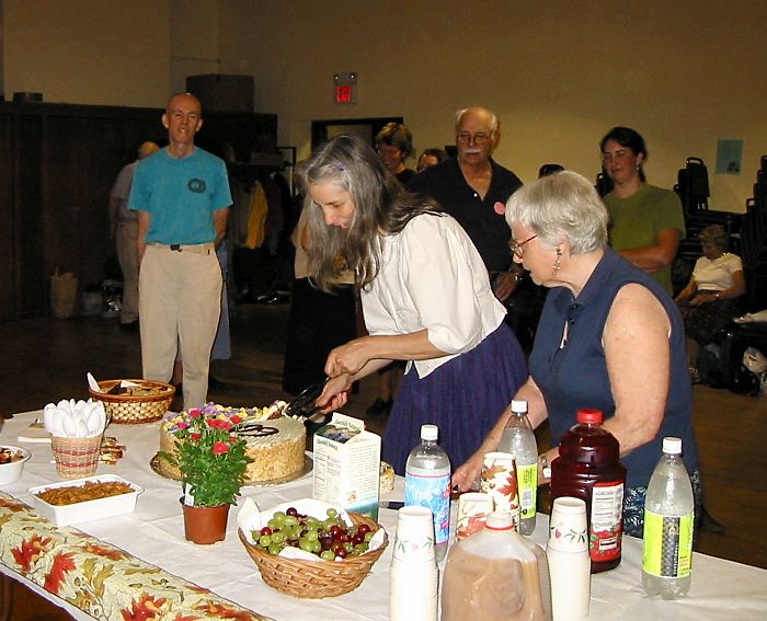 Susan Murrow cuts the cake while Fired watches.